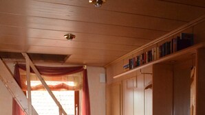 A wooden staircase leading to an upper floor, a kitchen area with wooden cabinets, and a window with curtains. - Ferienwohnung Westphal (Eschwege)