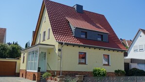 A two-story house with a red-tiled roof, a front porch, and a brick base. - Ferienwohnung Westphal (Eschwege)