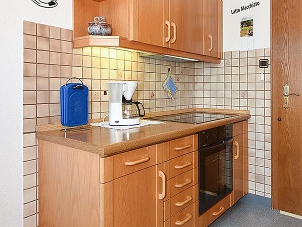A kitchen with wooden cabinets, a coffee maker, and a blue appliance on the counter.