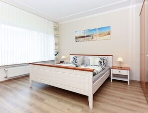 Un dormitorio con cama, mesitas de noche y una ventana con persianas.