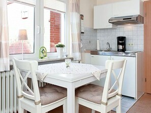 A compact kitchen with white cabinetry, a stove, and a coffee maker.