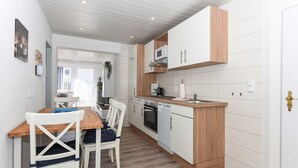 A compact kitchen with white cabinets, a wooden countertop, and a built-in microwave. - Ferienwohnung 6 - Haus Windliese (Esens)
