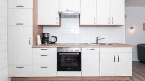 Une cuisine moderne avec des meubles blancs, un four Bosch, une machine à café et un évier.