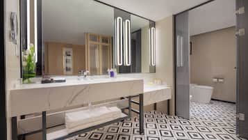 Un baño moderno con un espejo grande, encimera de mármol y baldosas de suelo estampadas.