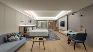 A modern hotel room with a large bed, a sofa, a small table, a TV, and a desk. - voco Guangzhou Shifu by IHG (Guangzhou)