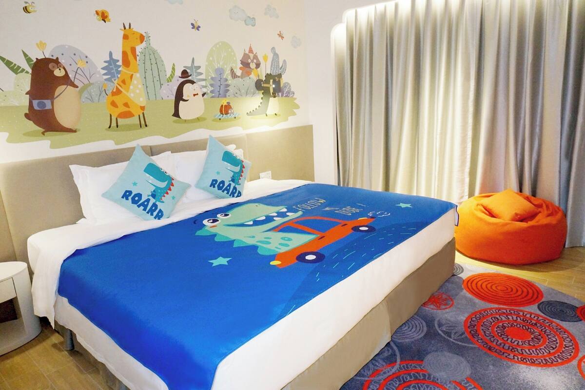 A child's bedroom with a bed, pillows, a bean bag, and a wall mural.