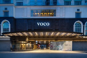 Ein modernes Gebäude mit einem gut sichtbaren "VOCO"-Schild über dem Eingang.