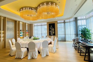 Uma sala de jantar espaçosa com uma mesa redonda posta para uma refeição, rodeada por cadeiras brancas.