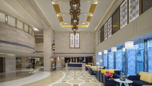 A spacious lobby with a reception desk, seating area, and a high ceiling with a modern chandelier. - voco Guangzhou Shifu by IHG (Guangzhou)