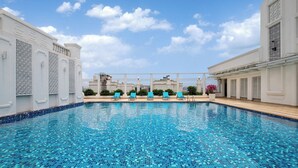 A swimming pool with tiled blue floor and white walls, surrounded by lounge chairs and a pergola. - voco Guangzhou Shifu by IHG (Guangzhou)