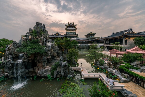Un jardín chino tradicional con cascada, estanque de carpas y arquitectura clásica.