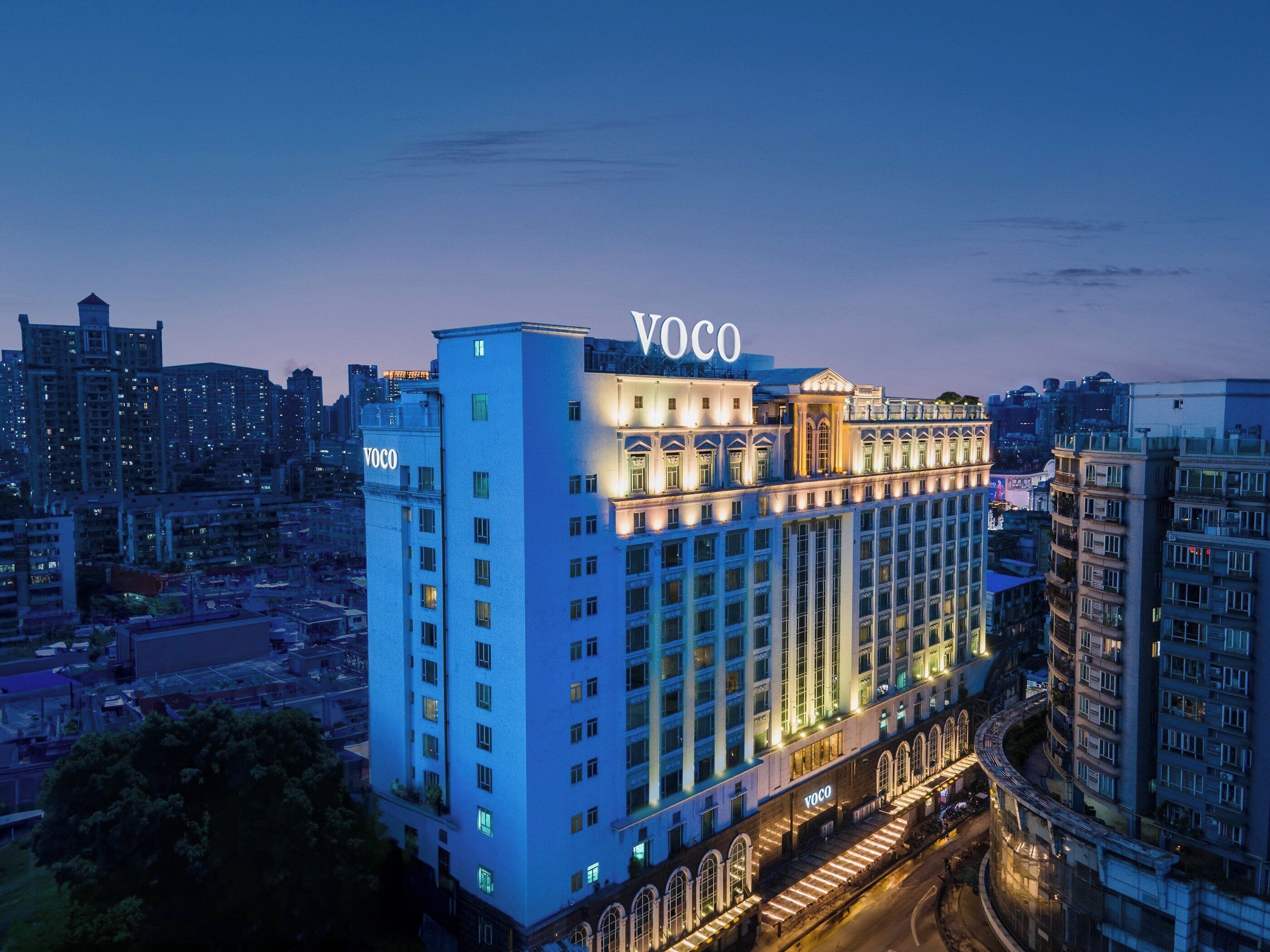 A high-rise hotel with 'Voco' signage, multiple floors, and a prominent entrance.