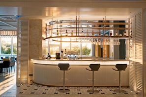 A modern bar area with a curved counter, multiple shelves of bottles, and bar stools. - voco Guangzhou Shifu by IHG (Guangzhou)