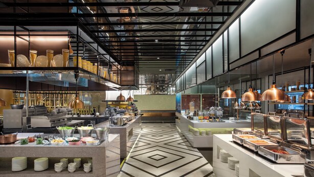 A modern kitchen with stainless steel appliances, buffet counters, and copper pendant lighting. - voco Guangzhou Shifu by IHG (Guangzhou)