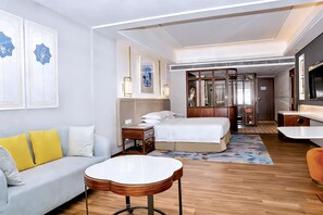 A hotel room with a bed, a sofa, a small table, and a TV. - voco Guangzhou Shifu by IHG (Guangzhou)