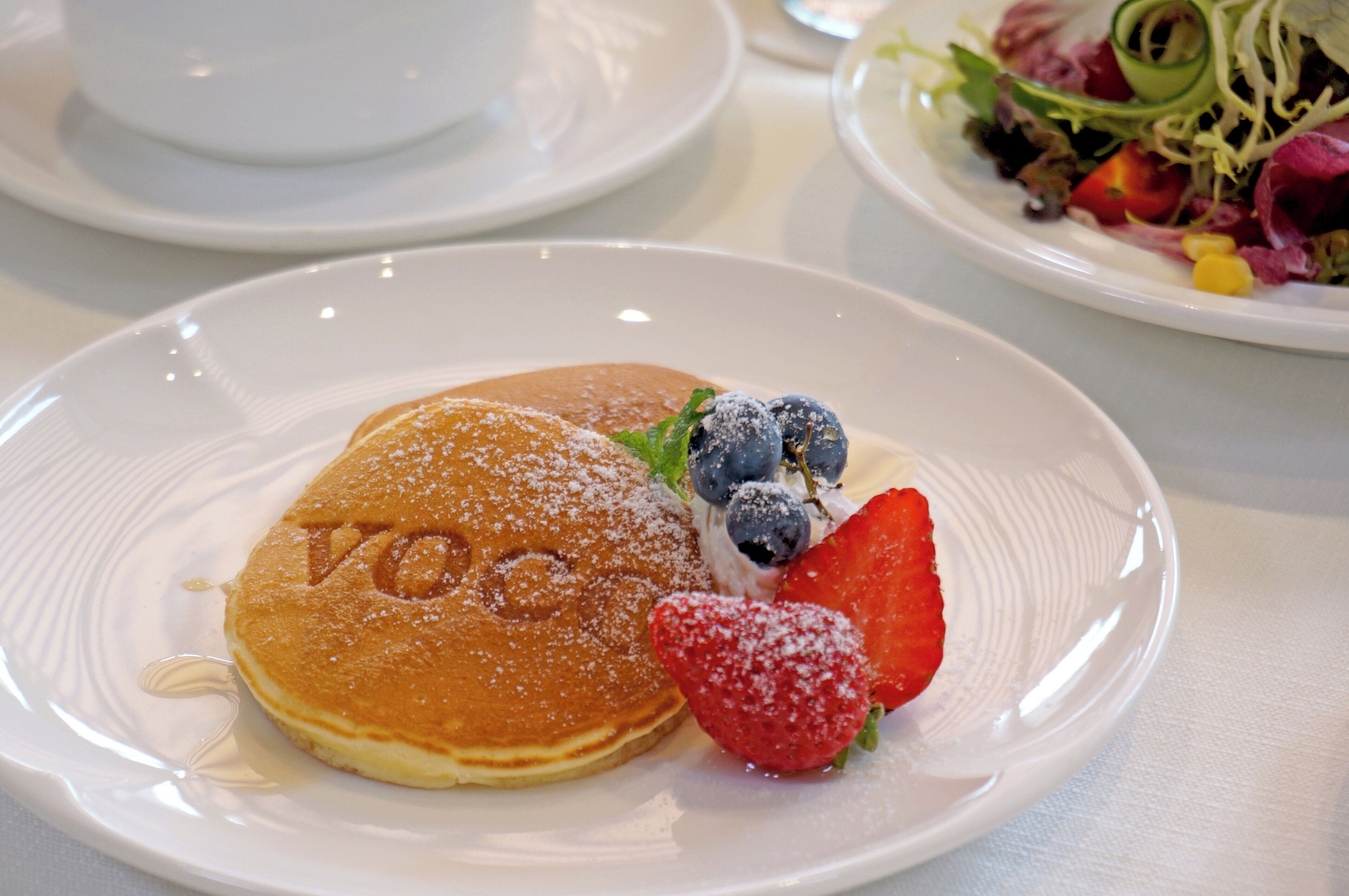 A breakfast plate with pancakes, blueberries, and a strawberry.