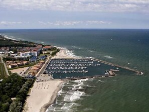 An aerial view of a coastal area with a marina, beach, and residential buildings.