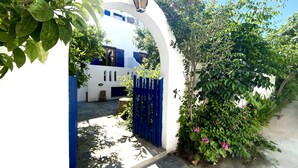 A white building with blue accents, a stone pathway, and a blue gate. - Helliniko Studios - Adults Only  (Paros)