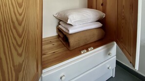 A wooden wardrobe with a built-in bed, featuring a white drawer and a shelf with pillows. - Helliniko Studios - Adults Only  (Paros)