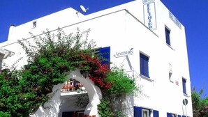 A white building with blue shutters, a sign reading "HOTEL," and an archway with greenery. - Helliniko Studios - Adults Only  (Paros)