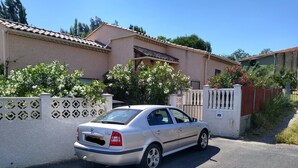 Une voiture argentée était garée devant une maison dont le toit était recouvert de tuiles et qui était agrémentée d’une clôture décorative.