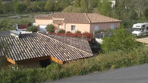 Un immeuble résidentiel avec un toit recouvert de tuiles, une cour clôturée et un camping-car garé.