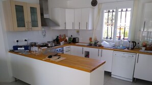 Une cuisine moderne avec des armoires blanches, un plan de travail en bois, une cuisinière encastrée et un lave-vaisselle.