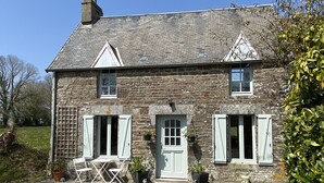 A stone house with a gravel driveway, a small garden, and a clear blue sky. - Le Petit Maison - La Relierie (Gavray)