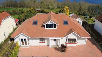 A two-story house with a red-tiled roof, a front porch, and a view of the sea.