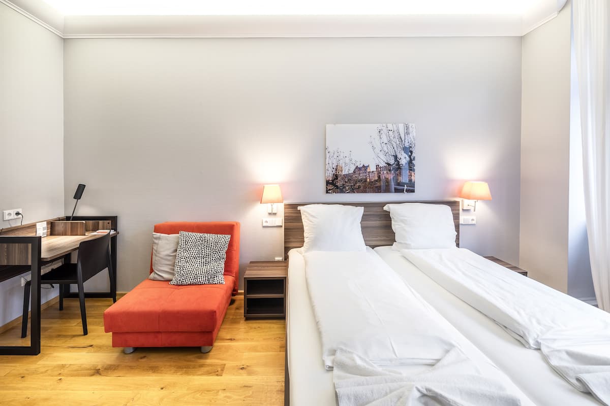 Une chambre d’hôtel avec un lit, un bureau, une chaise et un petit canapé.