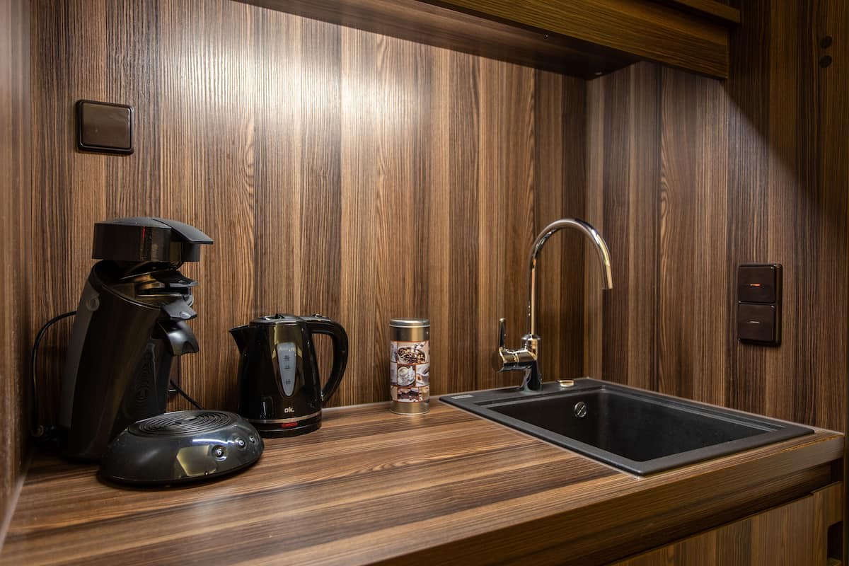 Une cuisine moderne avec un revêtement mural en bois, une machine à café, une bouilloire et un évier.
