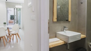 Un baño moderno con un espejo grande, un lavabo blanco y una zona de ducha.