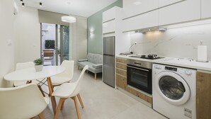 Una cocina moderna con lavadora integrada, un comedor con mesa y sillas, y un sofá gris.