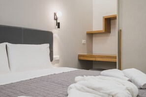 Habitación de hotel moderna con cama, mesita de noche, lámpara de pared y estante de madera.