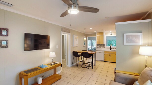 Une cuisine moderne avec un coin repas, un ventilateur de plafond et un téléviseur fixé au mur.
