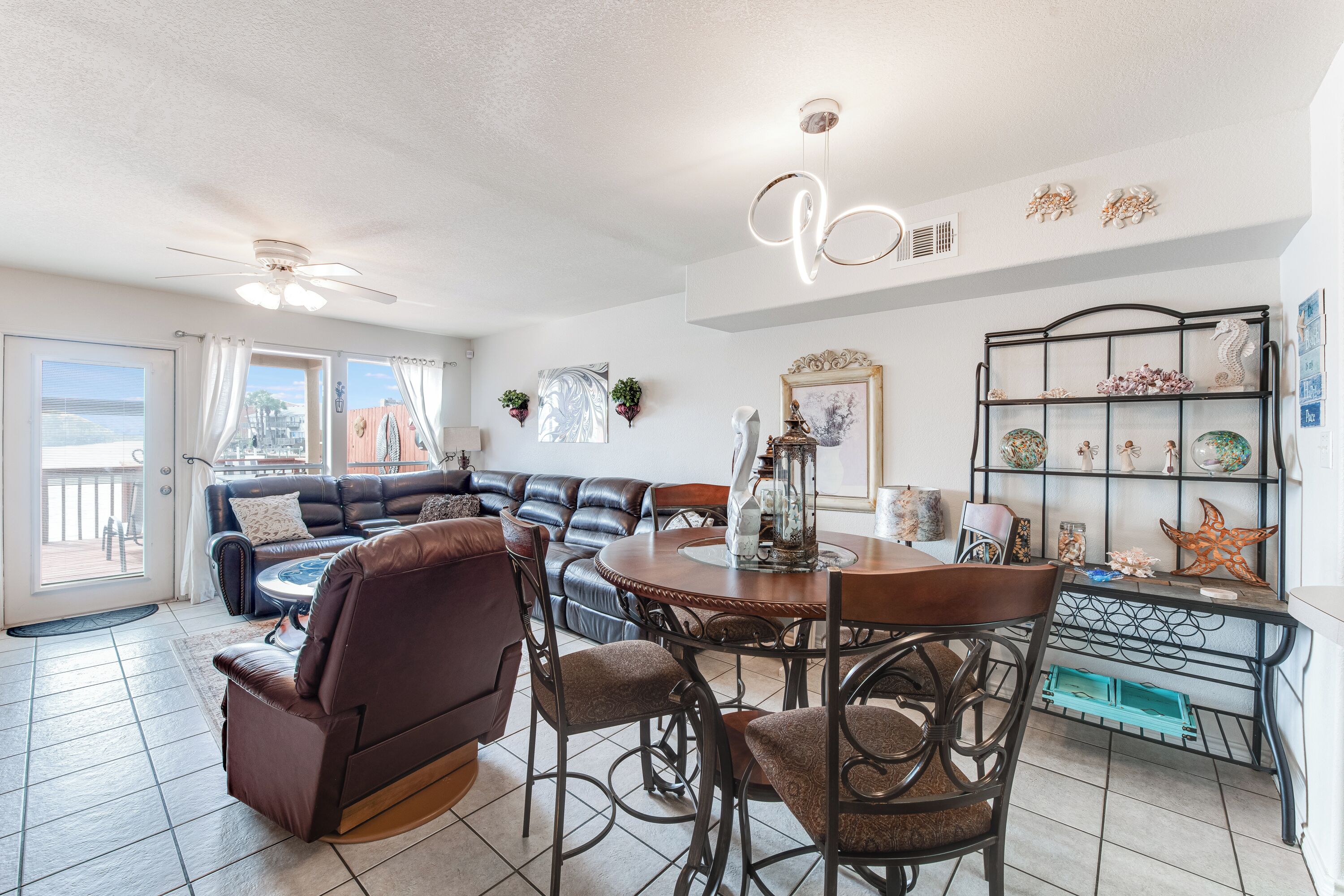 A spacious living area with a dining table, leather sofa, and a decorative shelf.