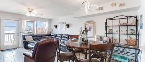 A spacious living area with a dining table, leather sofa, and a decorative shelf.