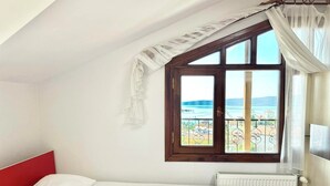 Un dormitorio con cama, ventana con vista al mar y radiador.