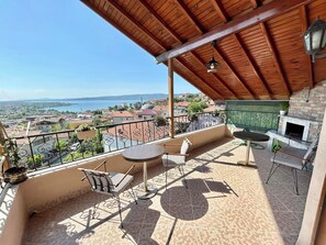 Un balcón con vista a un cuerpo de agua, una chimenea de ladrillo y mobiliario exterior.
