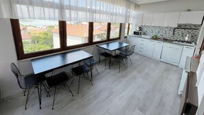 Una cocina moderna con armarios blancos, encimera negra y vistas a la ciudad a través de amplios ventanales.