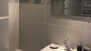 A bathroom with a white sink, a handheld showerhead, and a mirror above the sink.