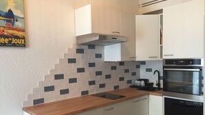 A modern kitchen with white cabinets, a wooden countertop, a built-in oven, and a tiled backsplash.