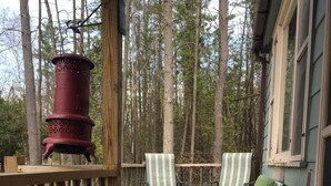 A wooden deck with two wicker chairs and a table, surrounded by trees. - house with beach and dock access (Willsboro)