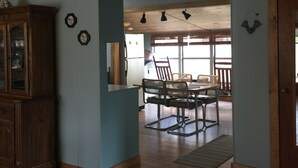 A spacious room with a wooden dining table and chairs, a cabinet with glass doors, and a ceiling with exposed beams. - house with beach and dock access (Willsboro)