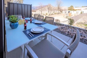 Enjoy a romantic meal for two in this serene outdoor dining area, complete with a table set and a beautiful neighborhood view.