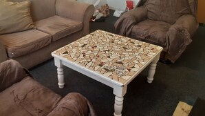 A living room with a brown sofa, a matching armchair, and a white coffee table with a mosaic pattern. - Tasumuka Savaal (Johannesburg)