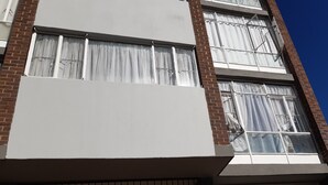 A multi-story building with large windows and a brick facade. - Tasumuka Savaal (Johannesburg)