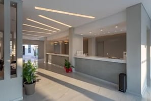 Ein moderner Empfangsbereich mit einer langen Theke, Topfpflanzen und einem klaren, minimalistischen Design.
