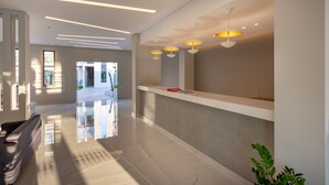 Un espace d’accueil moderne, doté d’un design épuré et minimaliste, comprenant un comptoir d’accueil, un éclairage suspendu et un sol poli.