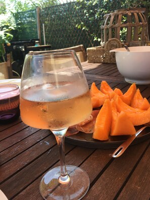 Un bicchiere di vino bianco su un tavolo di legno con un piatto di fette di cantalupo.